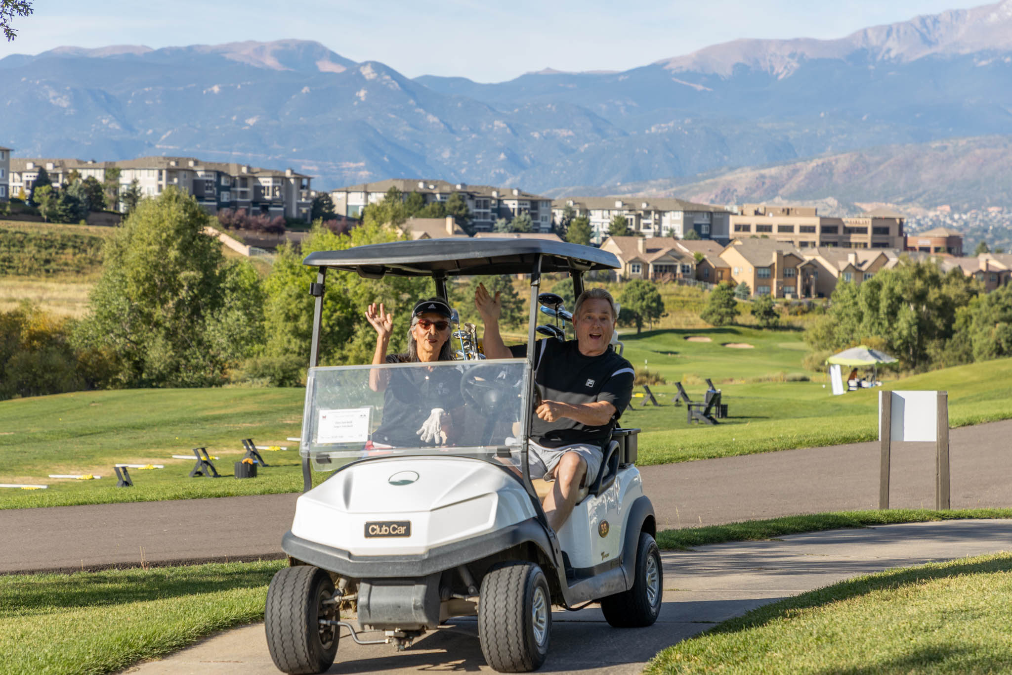 Dan and Joyce Satchell of Footprint Floors riding in a golf cart with mountains in the background at Pine Creek Golf Club in Colorado Springs at the Heartland Connect Golf Tournament