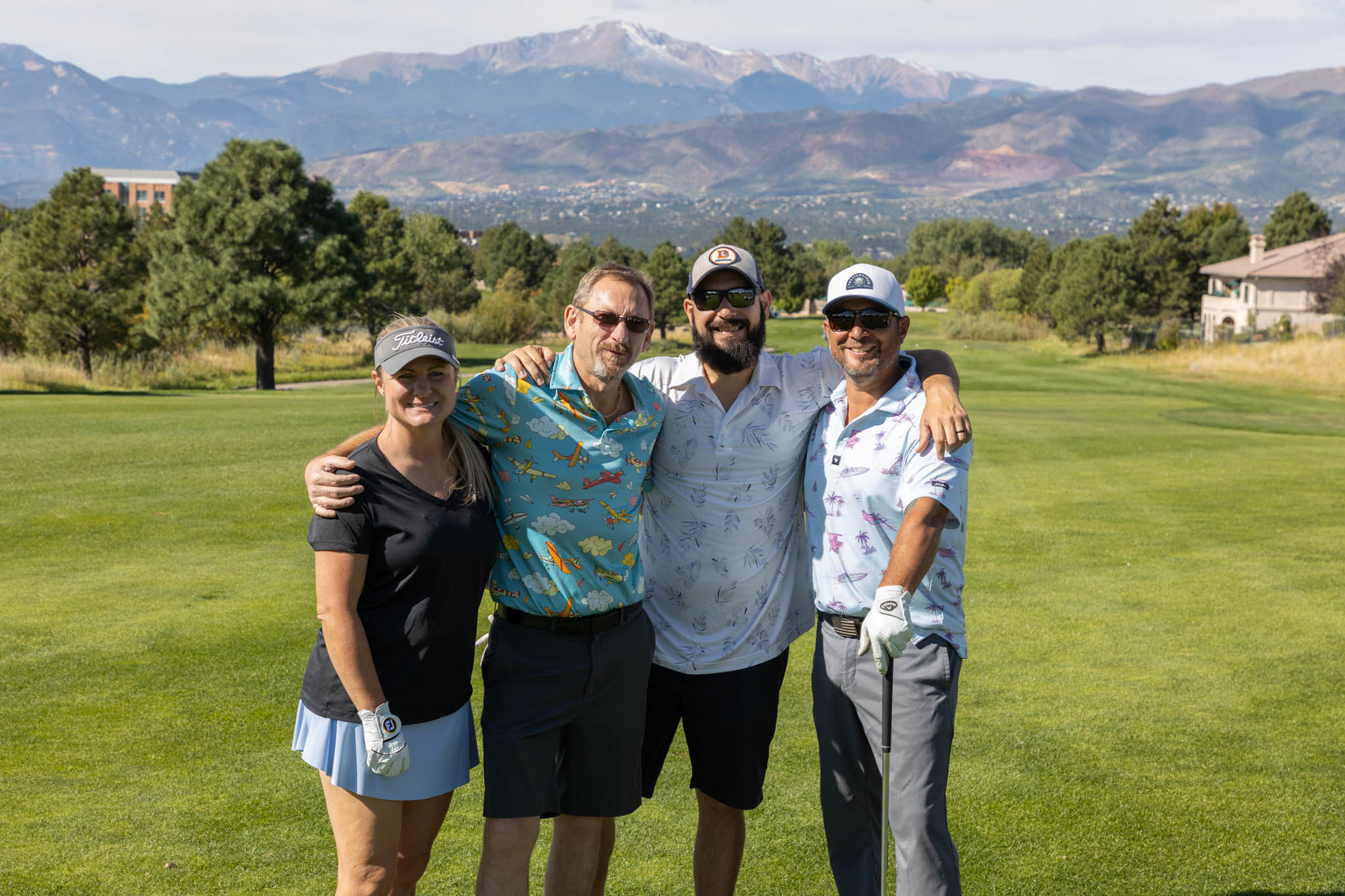 Four people posing for a photo on a golf course.
