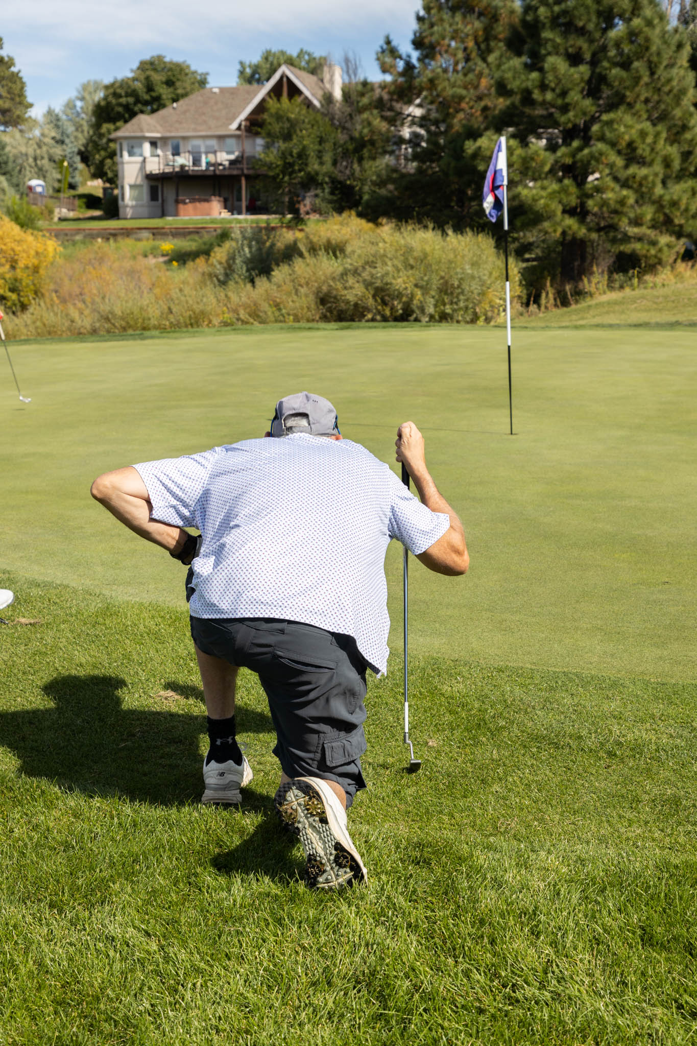A man crouching down on a golf course.